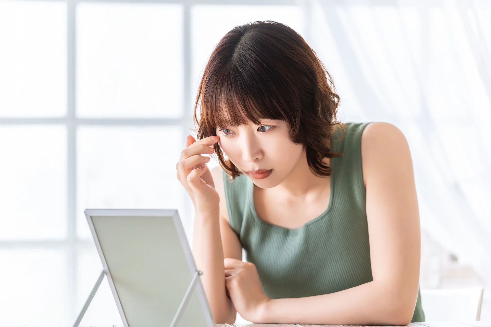 鏡で顔をチェックする女性