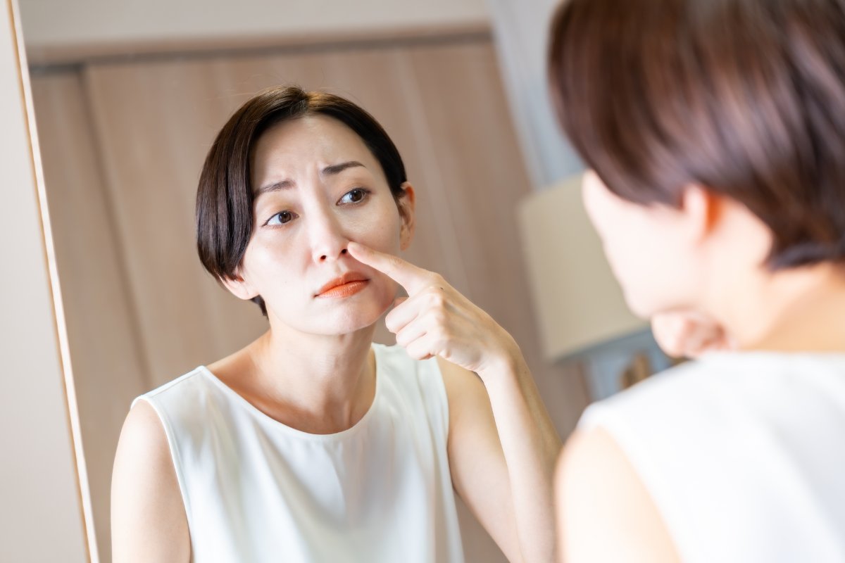 鏡を見ながら鼻に触れる女性