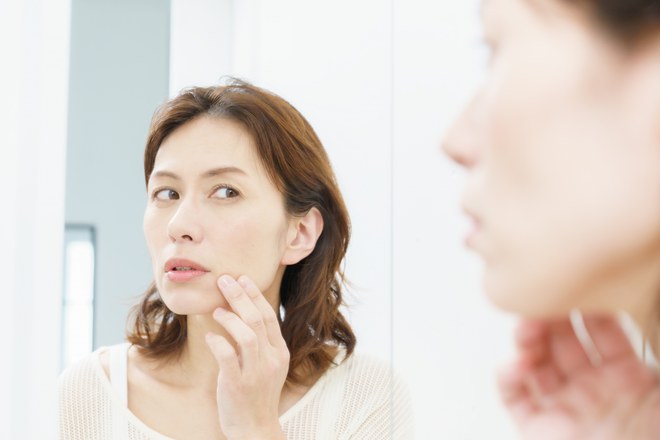 鏡でほうれい線を確認する女性